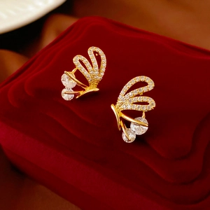 Close-up of golden butterfly earrings with zircon stones on a red velvet jewelry box