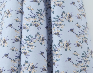 Detailed macro view of light blue fabric with white floral prints and bee patterns