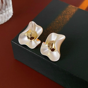 Detail of silver wavy metal earrings with gold faceted bead on a black gift box