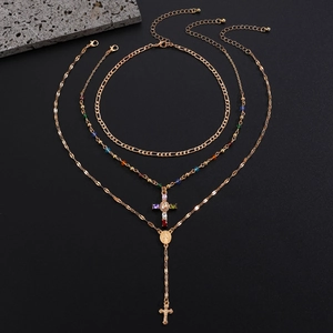 Detailed view of gold layered necklaces with cross pendants and colorful beads