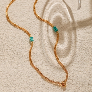 18K gold plated chain necklace with turquoise beads on textured background
