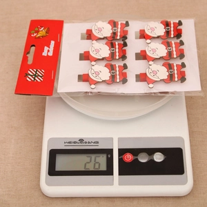 Close-up of 6 Santa Claus wooden clips on a scale showing 26g weight for Christmas decor