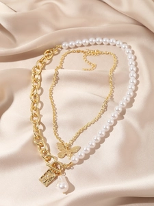 Close-up of layered baroque pearl necklace with gold lock and butterfly pendants on silk