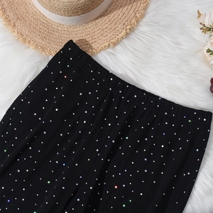 Close-up of black mesh flared pants with colorful rhinestones and elastic waist