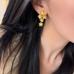 Elegant gold flower earrings with sparkling zircon crystals worn by a female model