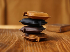 Stack of four colorful leather mini tape measures on a rustic wooden table background