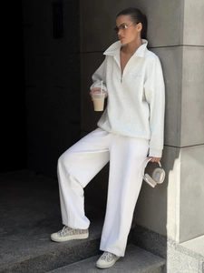 Detail of grey quarter-zip sweatshirt with 'loves' embroidery and white wide-leg joggers