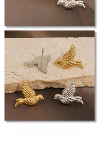 Detailed view of bird-shaped stud earrings in gold and silver plating with feather textures