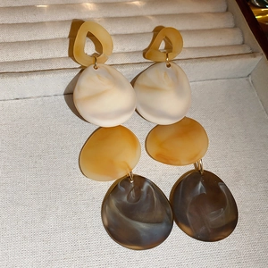 Close-up of geometric acrylic drop earrings with marble texture in a jewelry box