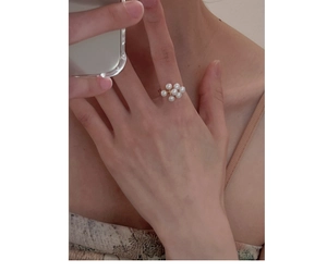 Close-up of golden ring with pearl cluster design worn on hand holding a mobile phone