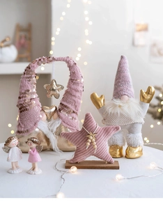 Close-up of pink Christmas gnomes and angel ornaments with warm bokeh lighting