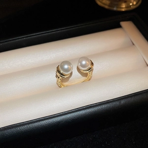 Detailed view of gold textured ring with two white pearls on a satin cushion display