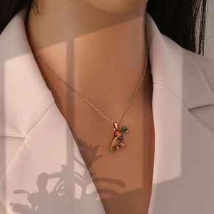 Detail of a gold parrot pendant necklace with colorful enamel inlay on a female model