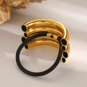 Detailed close-up of polished gold stainless steel tubes on a black elastic hair tie