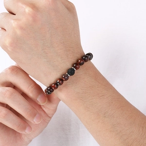 Close-up of red tiger eye and volcanic stone beaded elastic bracelet on a wrist