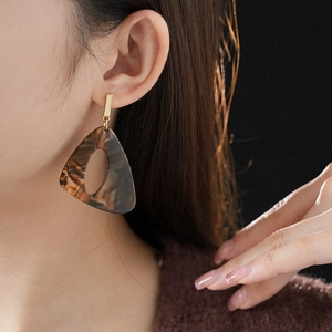 Macro shot of brown tortoise shell acrylic triangle earring with gold metal connector