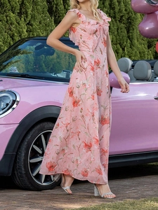 Robe longue en mousseline fleurie rose avec bretelles à volants devant une voiture rose