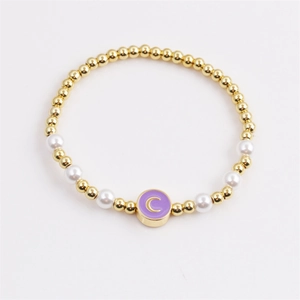 Fashionable gold beaded bracelet featuring white pearls and a purple moon enamel pendant