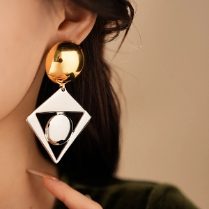 Detailed view of oversized geometric earrings in gold and silver mixed metallic finish