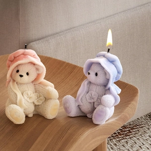 Detail of lit bear candles with knitted cloaks on a wooden stand in a cozy setting