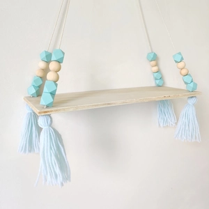 Detail of wooden wall shelf with light blue beads and decorative tassels in Nordic style