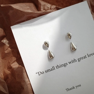 Macro view of silver teardrop stud earrings set in two sizes on decorative gift card