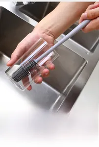 Detail of long-handled gray silicone brush cleaning the interior of a glass bottle