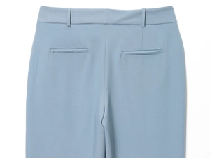 Dettaglio dei pantaloni azzurri a vita alta con tasche a filetto e passanti per cintura