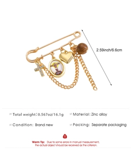 Dettaglio della spilla vintage oro con croce, ciondolo religioso, cuore e catenelle