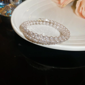 Detail of multi-layered pearl bracelet with sparkling diamonds on a white ceramic plate
