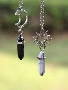 Detailed view of sun and moon pendants with hexagonal obsidian and white turquoise stones
