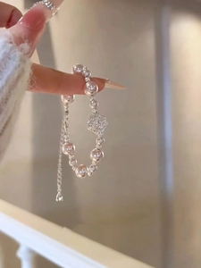 Détail d'un bracelet en perles avec charm fleur argentée et chaîne de réglage ajustable