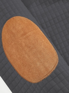Close-up of dark grey quilted fabric with brown elbow patches on the knit sweatshirt
