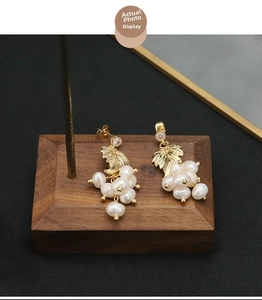 Detailed macro shot of vintage grape-shaped pearl earrings with gold leaf and zircons