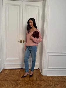 Pink V-neck knit sweater with lace trim paired with blue high-waist jeans and red heels