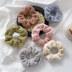 Set of 6 knitted scrunchies in autumn colors like brown and pink on a textured fabric