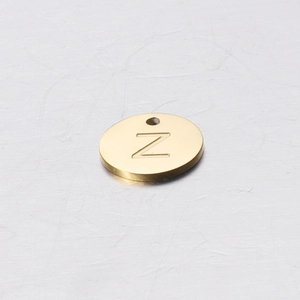 Detail of a 12mm gold stainless steel round charm with an engraved letter Z on a textured background