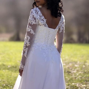 Elegant white long sleeve lace bridal gown with V-back and lace-up details for beach wedding
