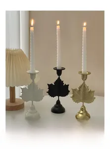 Detail of leaf-shaped metal candle holders in white, matte black, and brushed gold