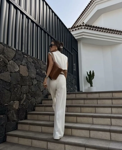 Rear view of white sleeveless vest and wide leg trousers set with a brown leather bag