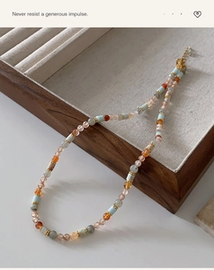Detail of beaded necklace with natural stones and agate on a wooden jewelry display