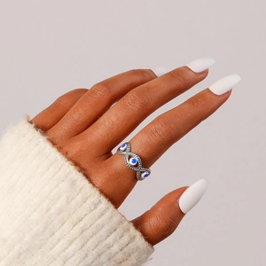 Detail of silver stainless steel open ring with blue and white evil eye pattern on hand
