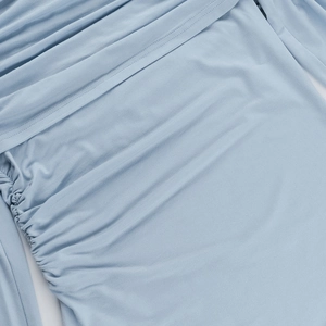 Detailed close-up of light blue knitted top showing ruching process and fabric texture
