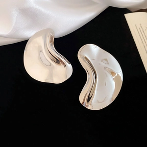 Detail of irregular silver earrings with a high-polished mirror finish on black silk