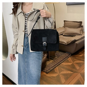 Detailed shot of retro matte black shoulder bag with silver buckle on suede texture