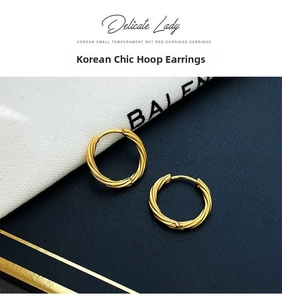 Detailed close-up of golden braided twist hoop earrings on a textured fabric backdrop