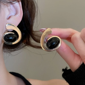 Detail of vintage gold oval tassel earrings with black inlay on model for a luxury look