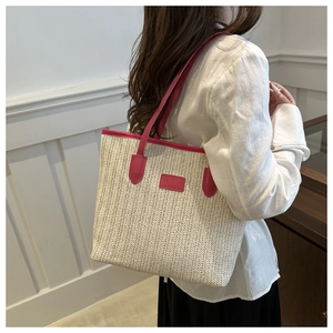 Detail of straw woven tote bag featuring magenta leather straps and spacious interior