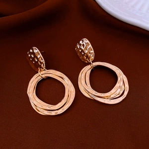 Macro detail of gold-plated multi-ring earrings with textured irregular oval studs