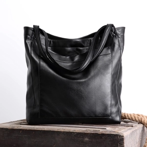 Détail du sac cabas vintage en cuir noir huilé avec poche sur un coffre en bois